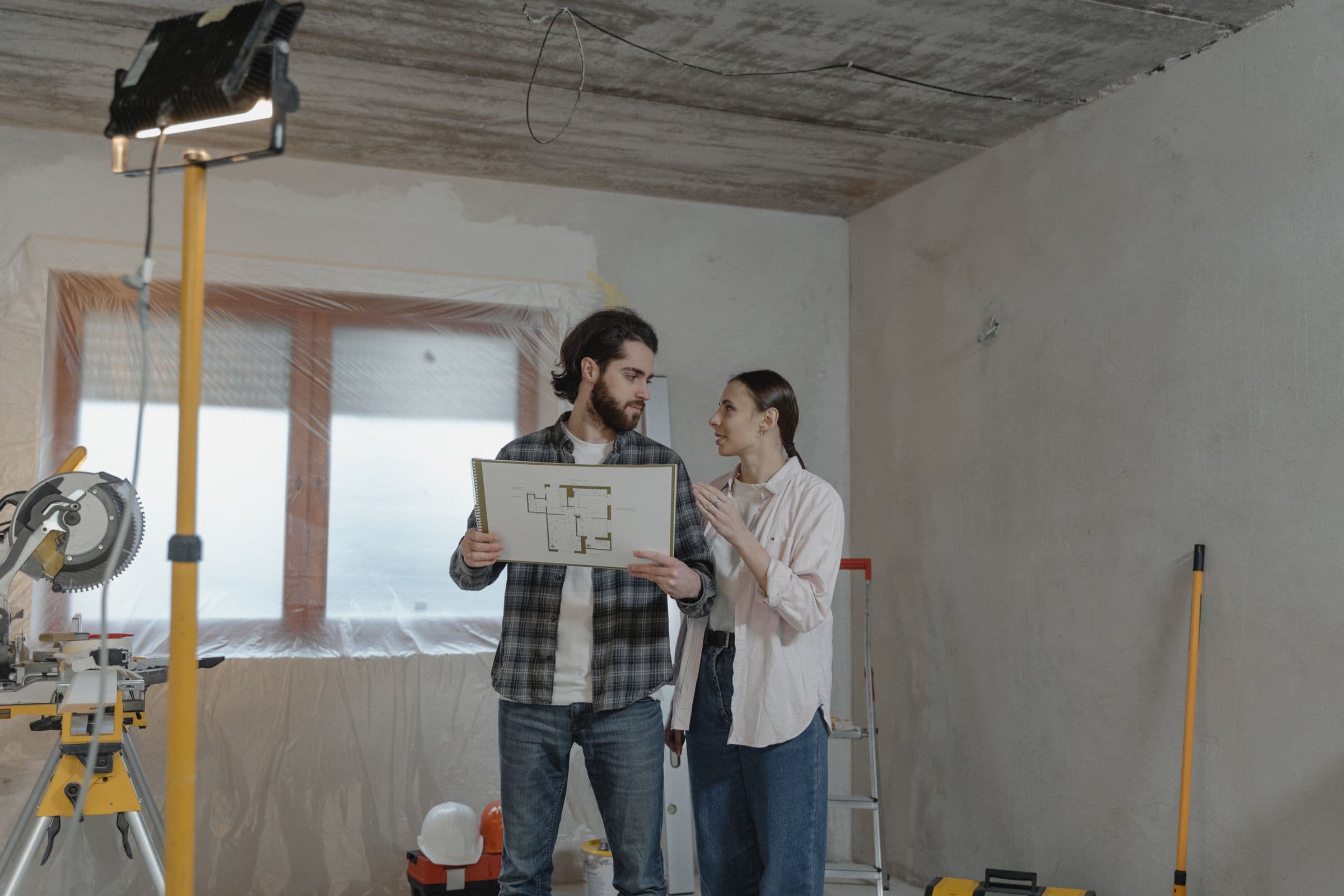 A couple reviewing renovation plans in a room under construction